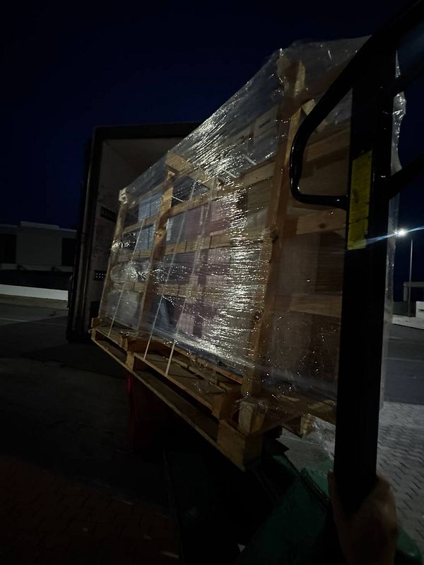 A large stone table is being unloaded from a truck at night.