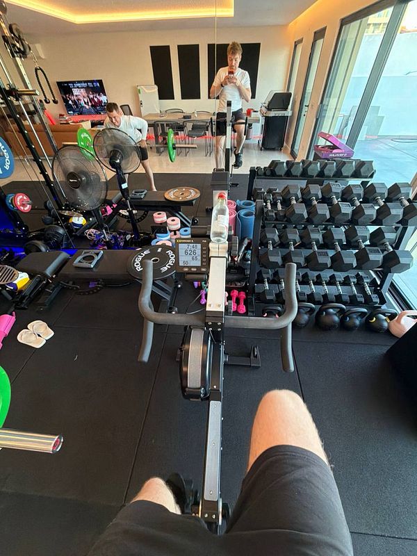 A home gym setup featuring various exercise equipment and two individuals engaged in workouts.