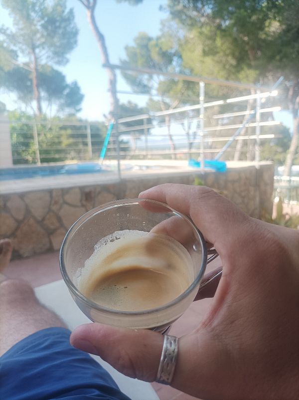 A person enjoys a late espresso while relaxing outdoors.
