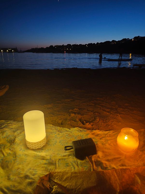 Sunset beach scene with a wooden table and chairs in the sand, overlooking the ocean.
