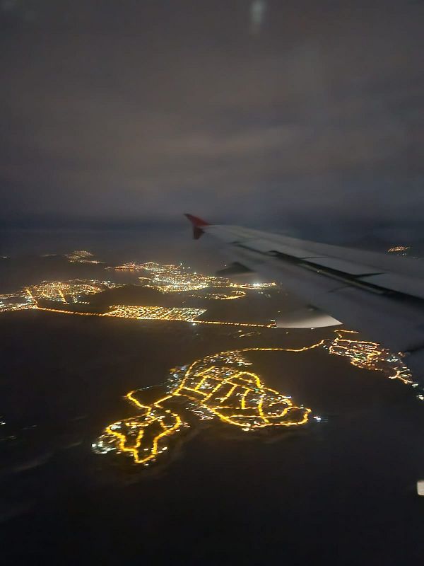 Passengers on a flight listen to an announcement as a civil red alert is triggered, with facial expressions showing concern.