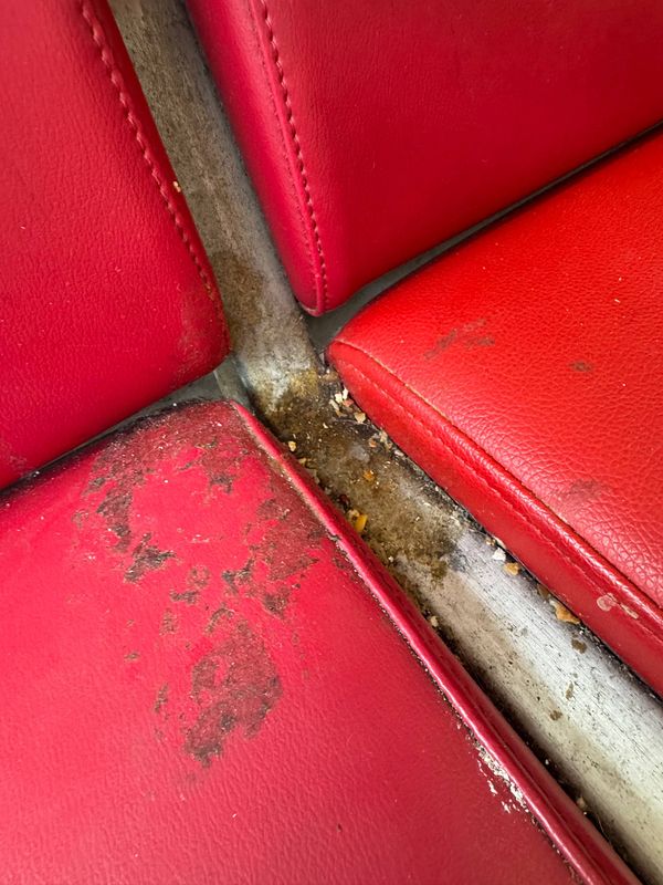 The image depicts a close-up view of a dirty seating area at Lisbon Airport.