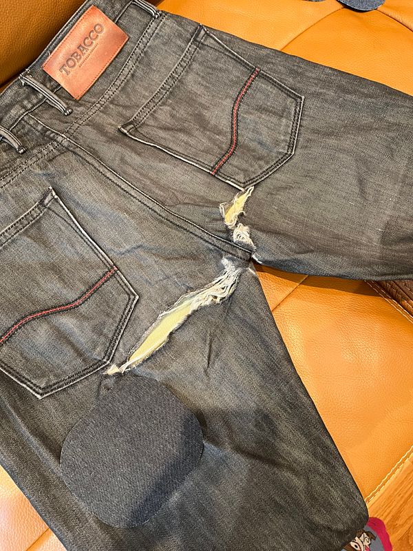 A pair of distressed moto pants with a patch ready for repair.