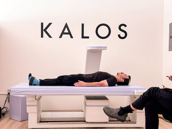 A man is lying on a DEXA scan table in a medical facility.