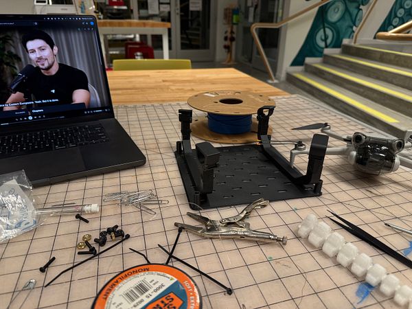 A workspace featuring a laptop, 3D printing materials, and tools for assembling a baseplate frame.