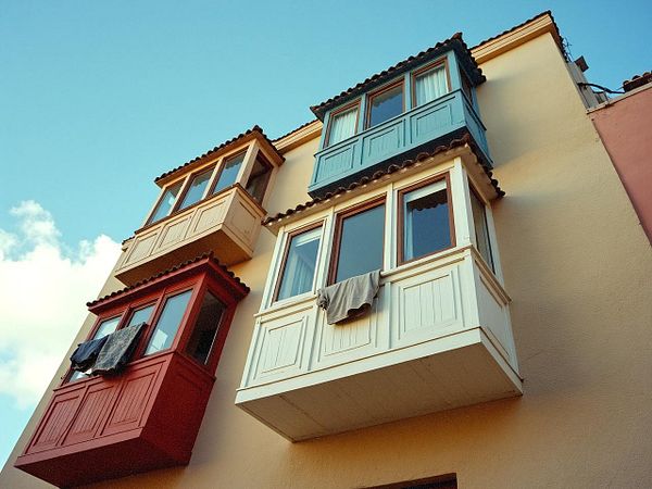 A colorful building facade featuring three distinct balconies.