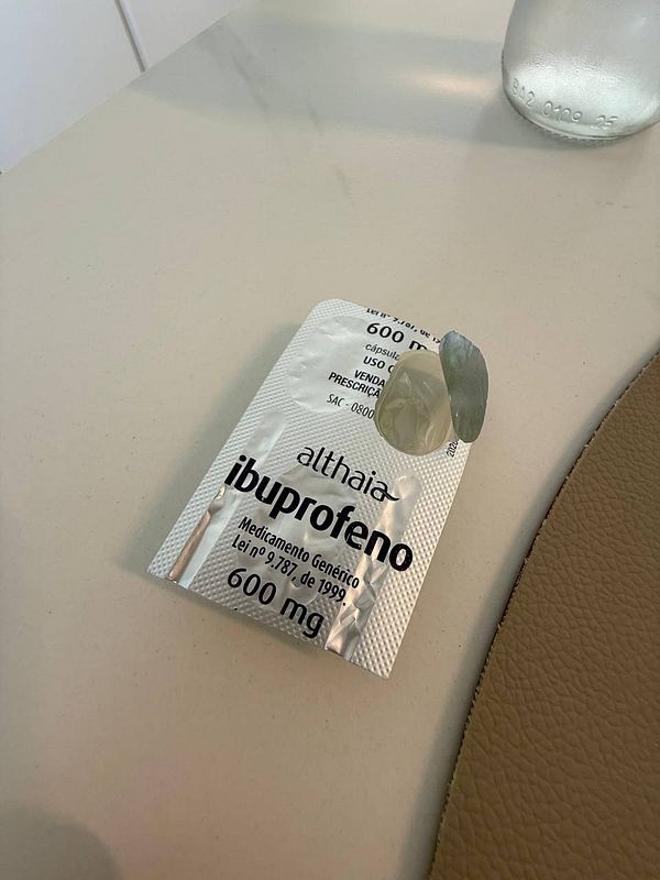 The image features a packet of ibuprofen and a capsule on a light-colored surface.