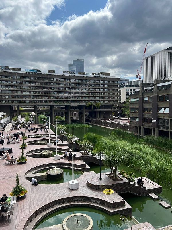 A scenic view of a modern urban area in London featuring a waterway and landscaped seating areas.