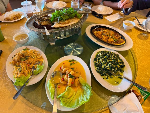 A variety of seafood and dishes are served on a large dining table for a family lunch at a seafood restaurant.