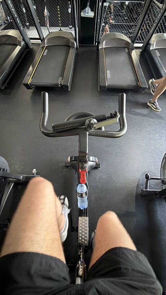 Photo of a muscular man in a gym flexing his biceps and smiling.