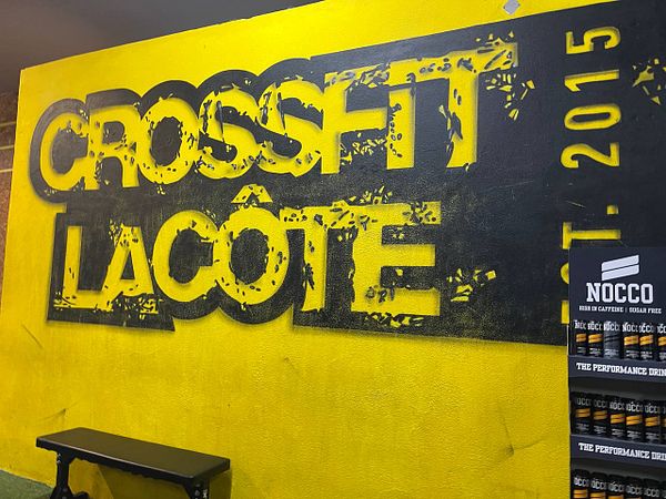 A vibrant wall mural featuring the CrossFit Lacôte logo and a display of NOCCO energy drinks.