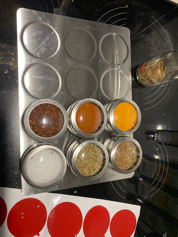 A neatly organized spice rack featuring various spices in glass containers on a metal tray.