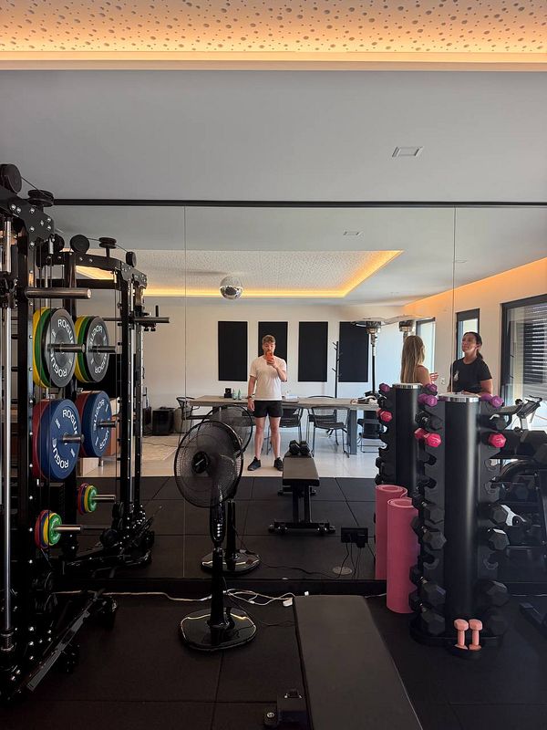 A gym scene featuring a person lying on a back extension bench, ready for a back workout, with gym equipment in the background.