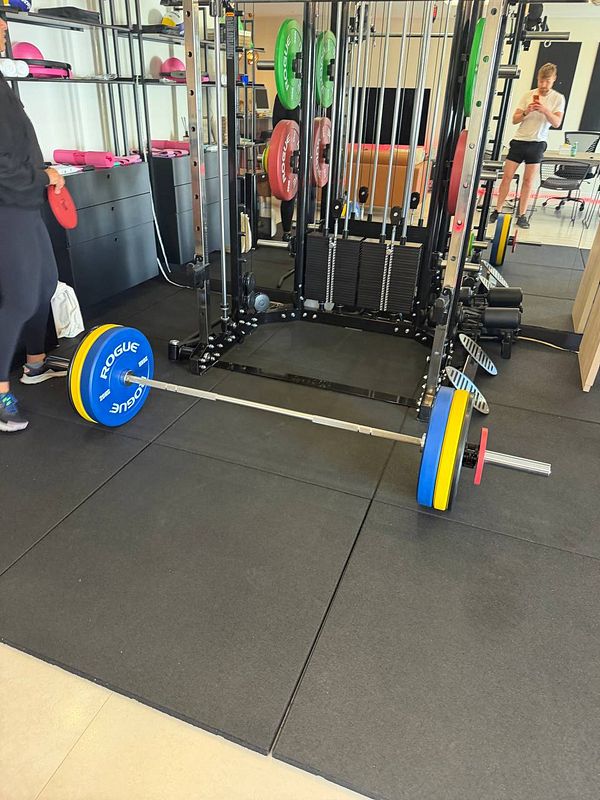 A man deadlifting a heavy barbell in a gym setting, viewed from behind.