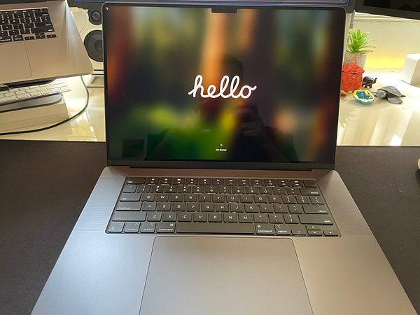 A new MacBook Pro is displayed with a 'hello' greeting on the screen.