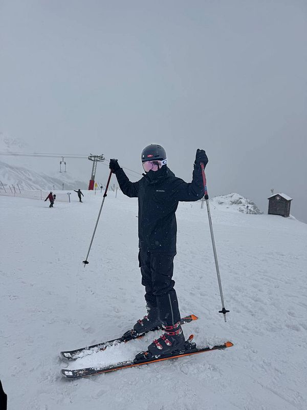 A skier stands on a snowy slope, ready to ski.