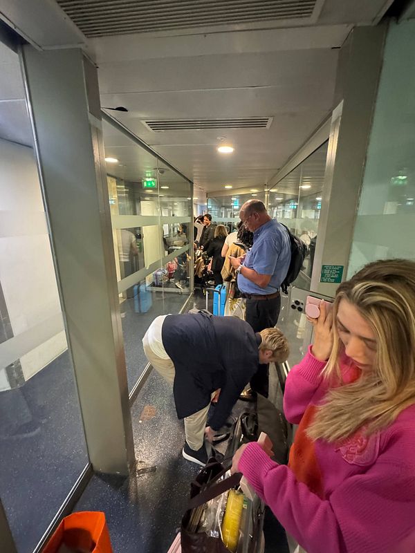 Passengers are waiting in a crowded jetway at an airport in Paris.