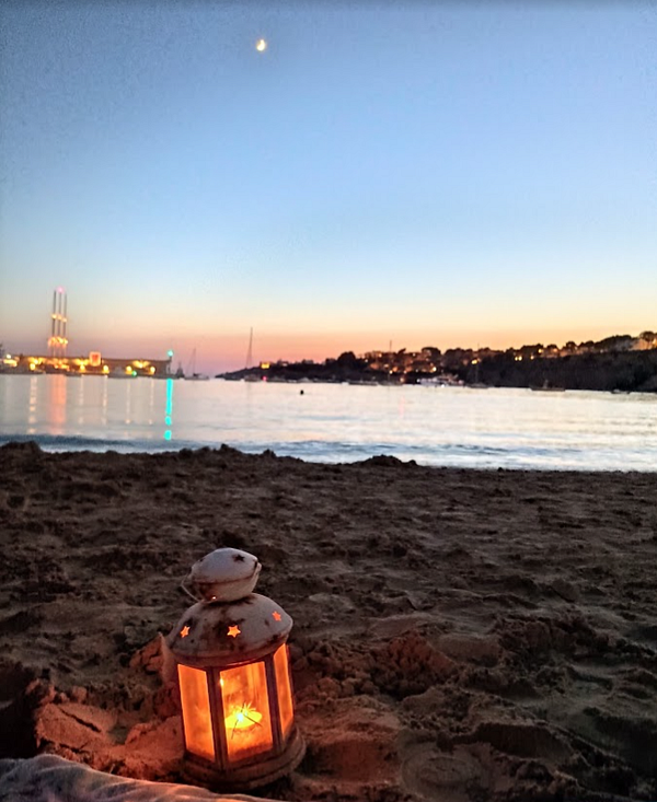 A serene beach scene at dusk featuring a lantern and a calm sea.