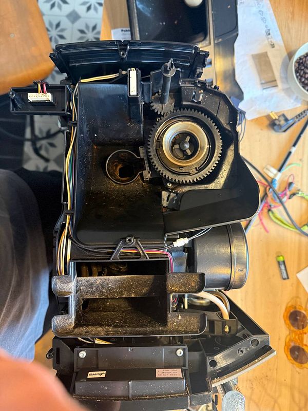 The image depicts the interior of a disassembled coffee machine, showing various components and wiring.