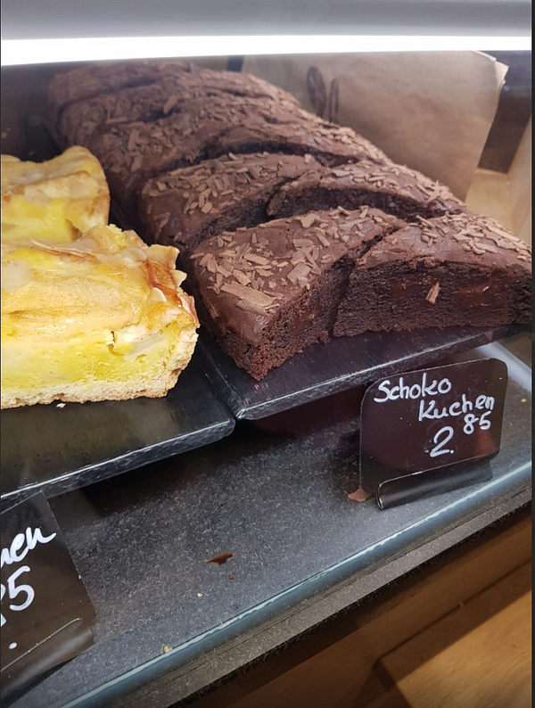 A display case featuring two types of baked goods: a yellow pastry and a chocolate cake.