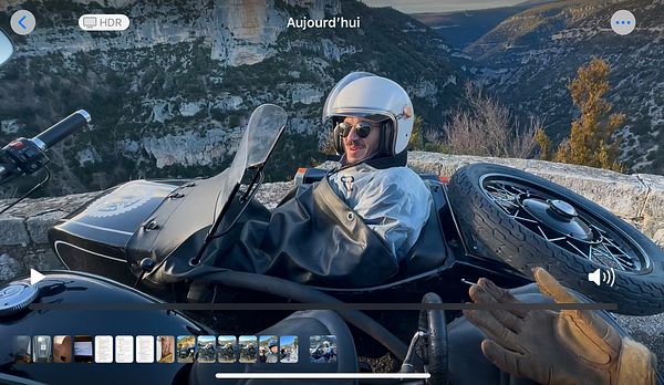 A person is enjoying a ride in a Ural sidecar motorcycle with a scenic mountainous backdrop.