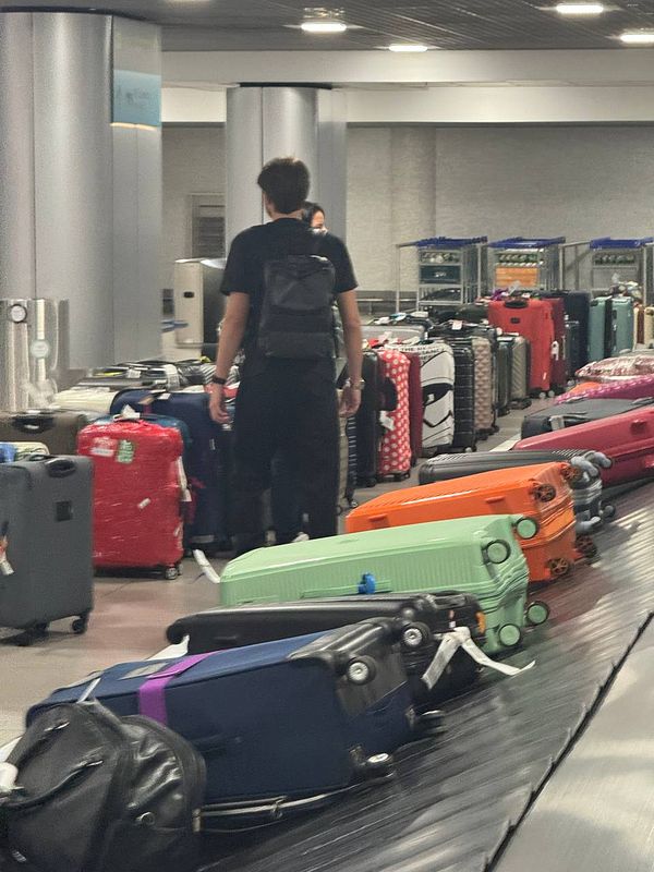 A chaotic scene at Lisbon Airport's baggage claim area with numerous suitcases scattered around.