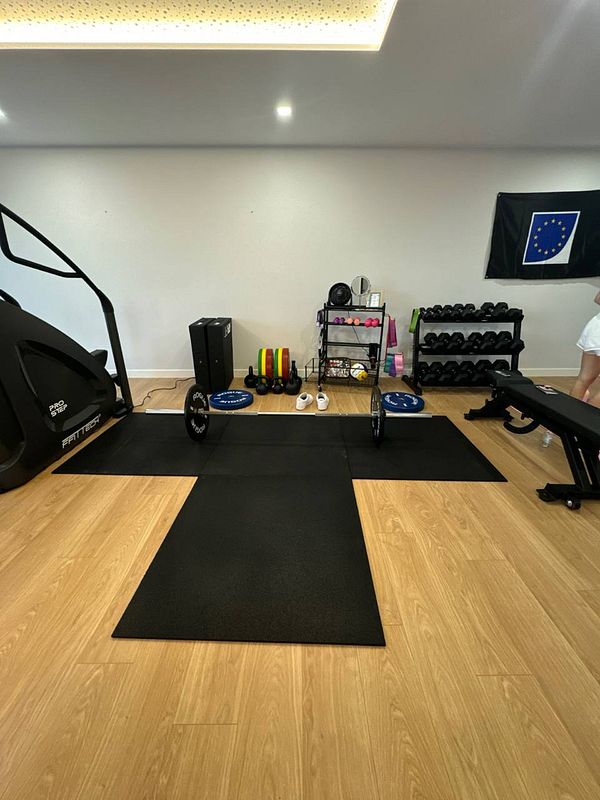 A home gym setup featuring various fitness equipment and a European flag.