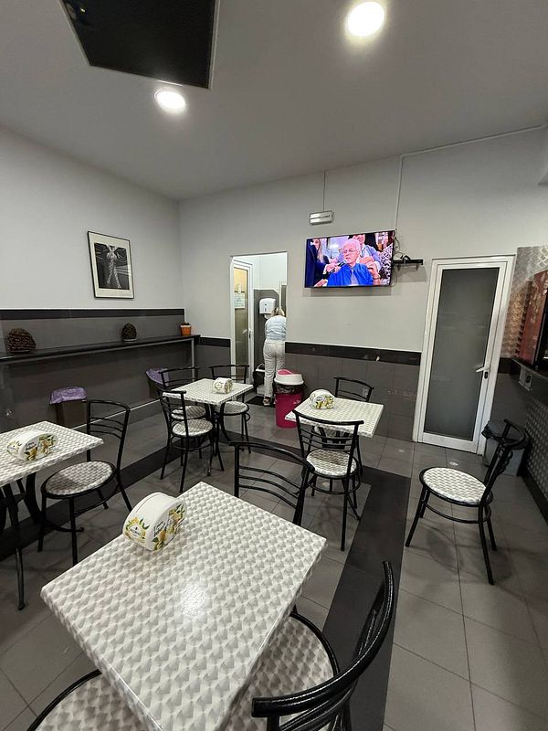 A small café interior with empty tables and a person at the restroom door.