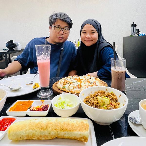 A couple enjoys a meal featuring a variety of dishes at a dining table.