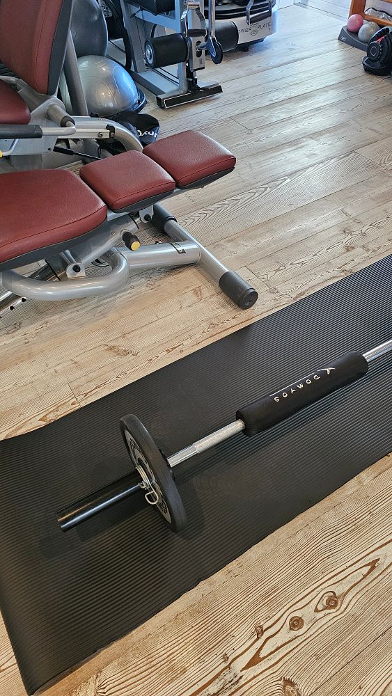 A weightlifting setup in a gym environment featuring a barbell and exercise equipment.