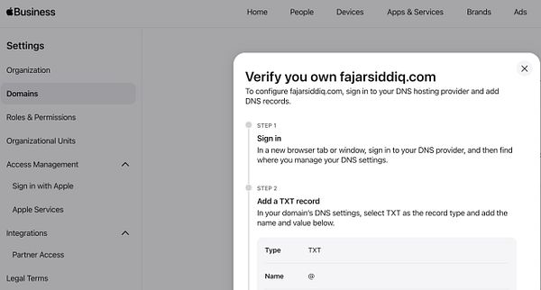 Screenshot of the Apple Business Manager's Domains verification page showing a domain ready to be verified with DNS configuration instructions.