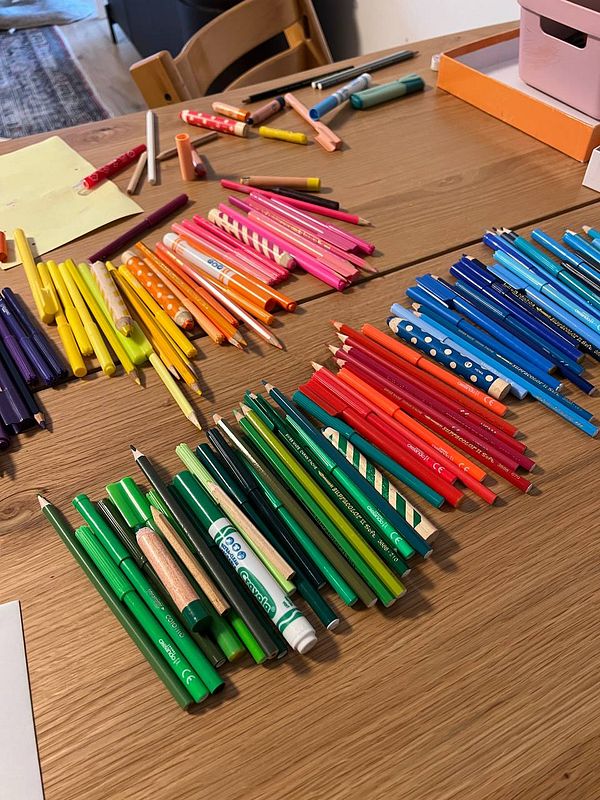 A colorful assortment of drawing tools is spread out on a wooden table.