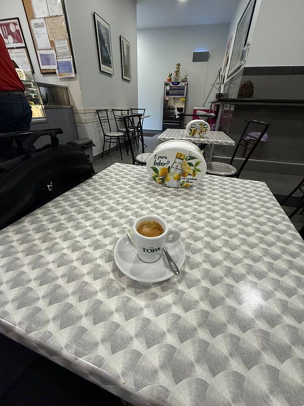 A coffee cup sits on a patterned table in a café near a driving license center in Portugal.