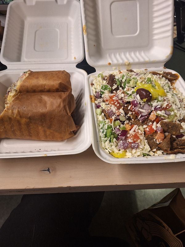 The image features two containers of Mediterranean street food, including wraps and a salad.