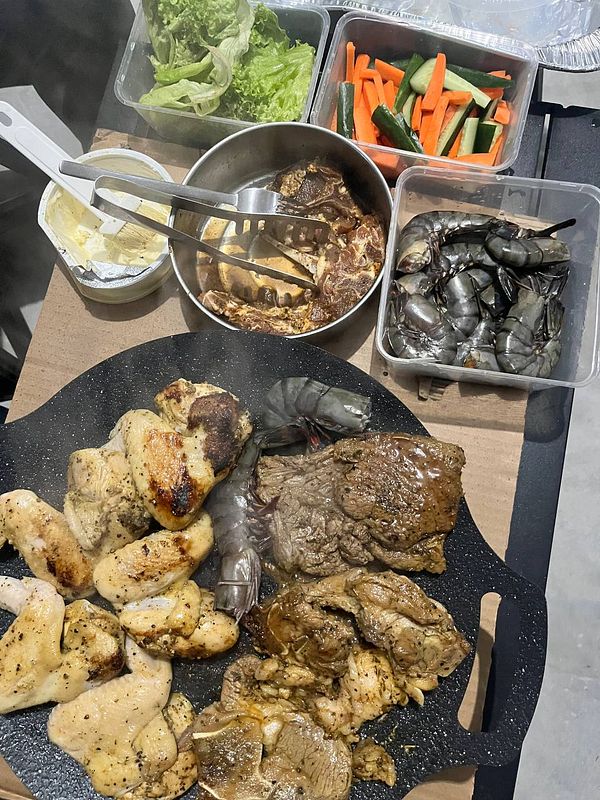 A variety of grilled meats and vegetables are arranged on a cooking surface.