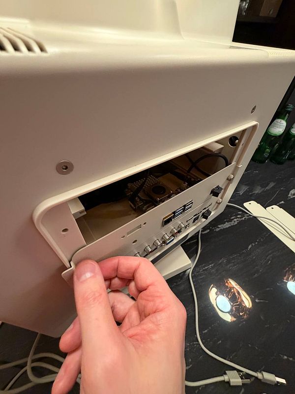 A person is accessing the back of a retro display to modify its internal components.