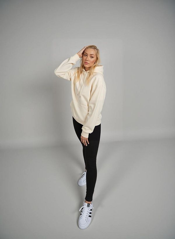 A young woman poses in a casual outfit against a neutral background.