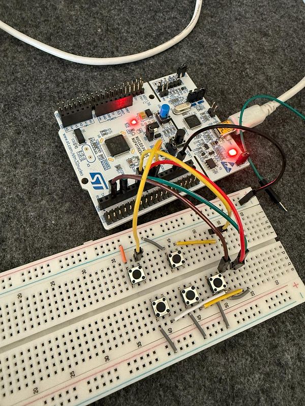 A prototype setup featuring an STM32 development board connected to a breadboard with navigation and shift buttons.