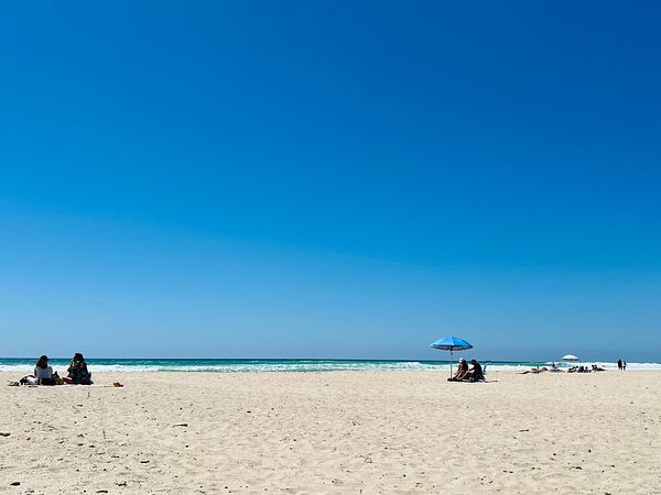 A serene beach scene with families enjoying the sun and ocean.