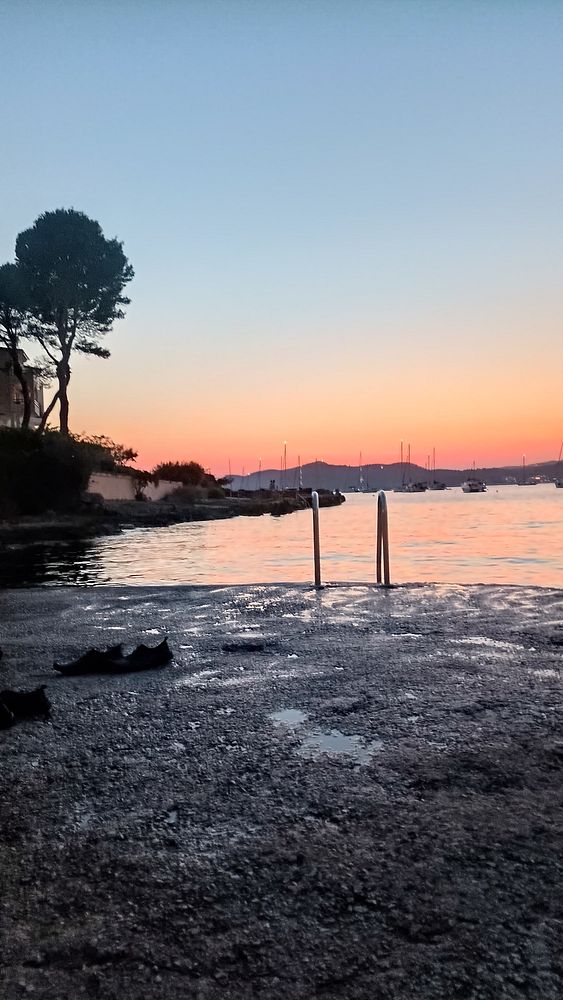 A serene sunset view by the water with a staircase leading into the sea.