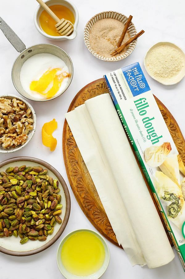 An assortment of ingredients and materials for preparing a dish, prominently featuring filo dough.