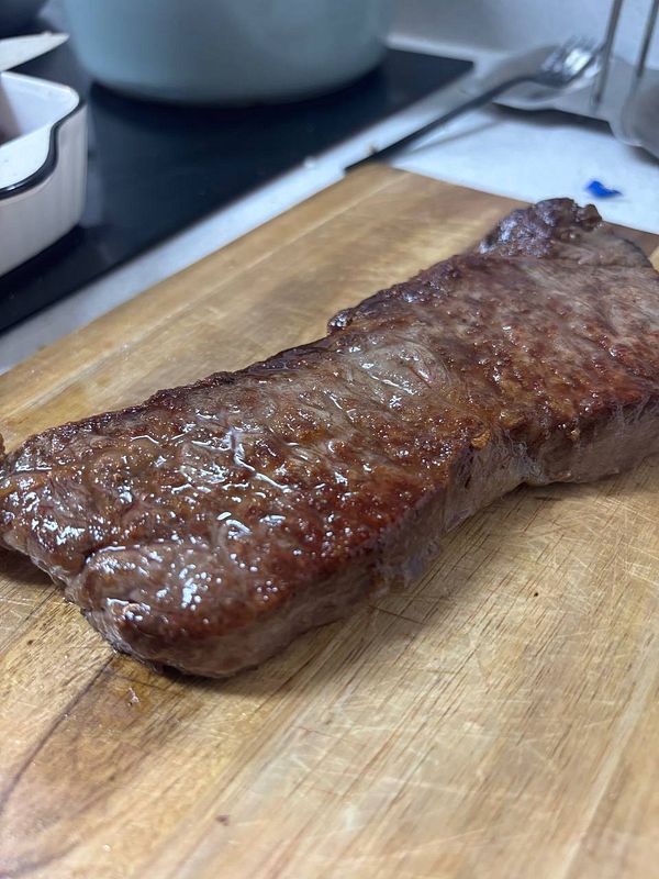 A perfectly cooked piece of hanwoo sirloin steak rests on a wooden cutting board.