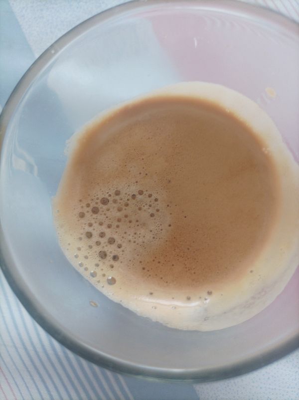 A close-up view of a glass containing espresso with a frothy surface.