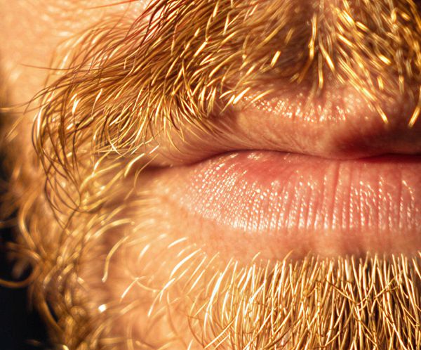 A close-up image of a person's lips and facial hair.
