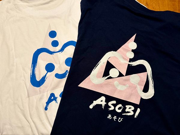 A close-up image of a T-shirt with a minimalist Buddha face print in white on a brown fabric.
