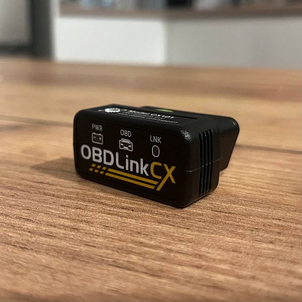 A sleek blue BMW sedan parked on a driveway near a garage with trees in the background.