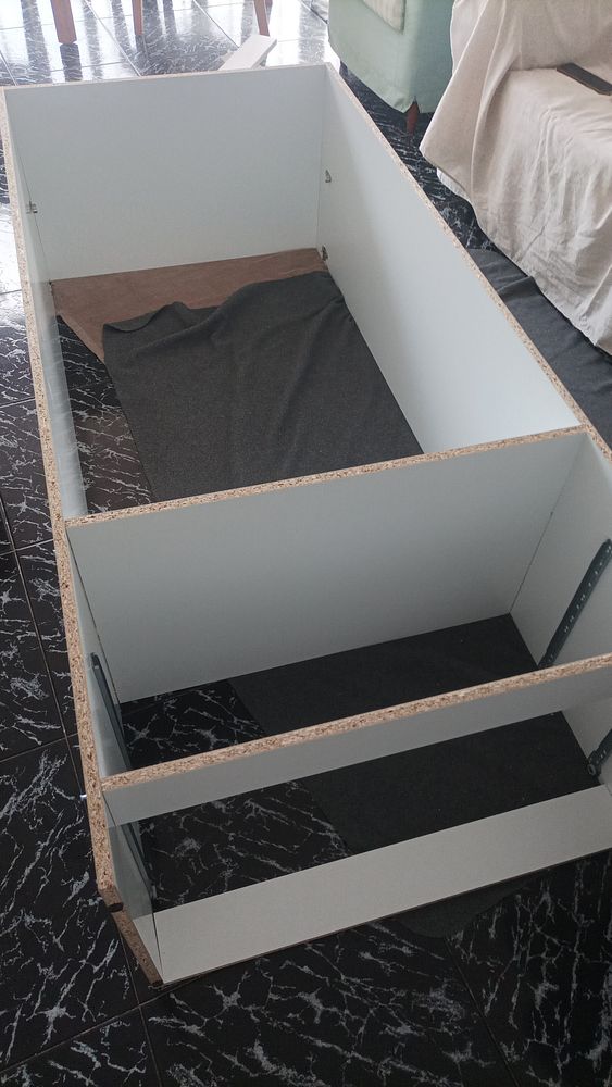 An image of various unassembled furniture parts and tools arranged on a floor.