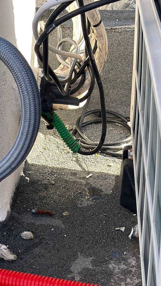 The image depicts a rooftop area with improperly installed electrical cables and tubing.