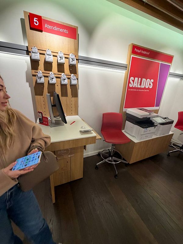 A customer is inside a Vodafone store, interacting with the service area while facing an issue with eSIM transfer.