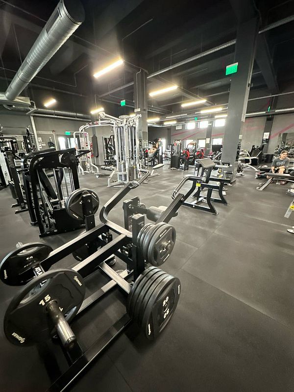 A modern gym interior filled with various workout equipment and people exercising.